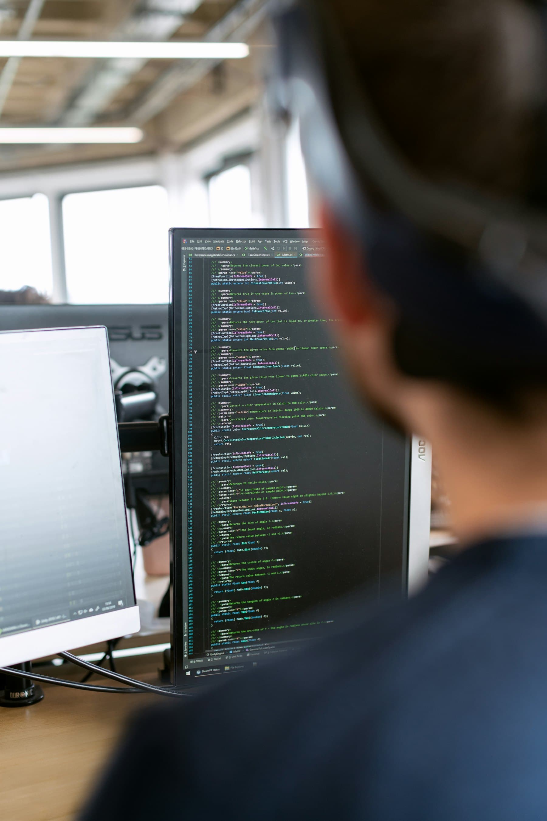 Engineer working at a multi-monitor workstation reviewing system output